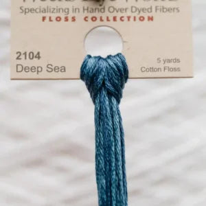 Deep Sea blue cotton floss with a label on a textured beige background.