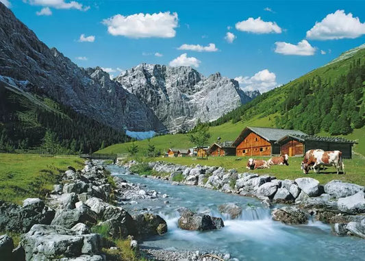 Scenic landscape with mountains, a stream, and wooden cabins.
Photo by Ravensburger [image_link]