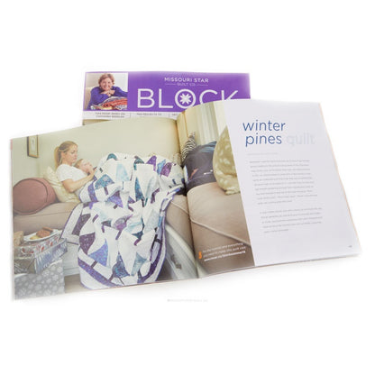 An open magazine or booklet spread showing a quilted blanket draped over a sofa, with a purple cover visible behind it reading MISSOURI STAR BLOCK. The right page has the headline 'winter pines quilt.
[additional_image_link]