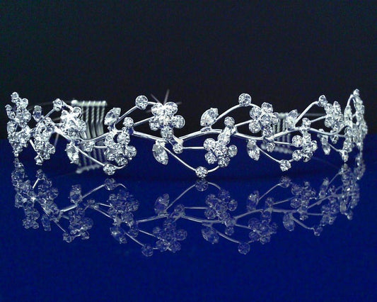 Silver tiara with floral design on a reflective blue surface
[image_link]