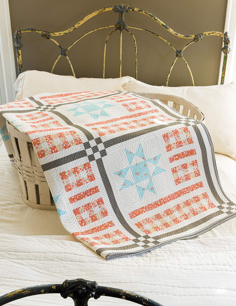 Quilt with star pattern draped over a bed with a metal headboard.
[additional_image_link]