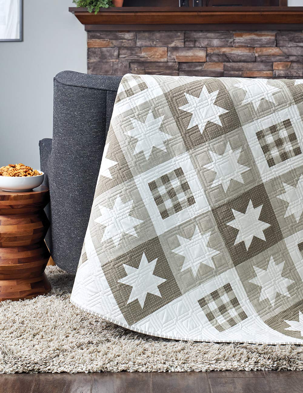 Quilt with star patterns draped over a chair in a living room setting.
[additional_image_link]