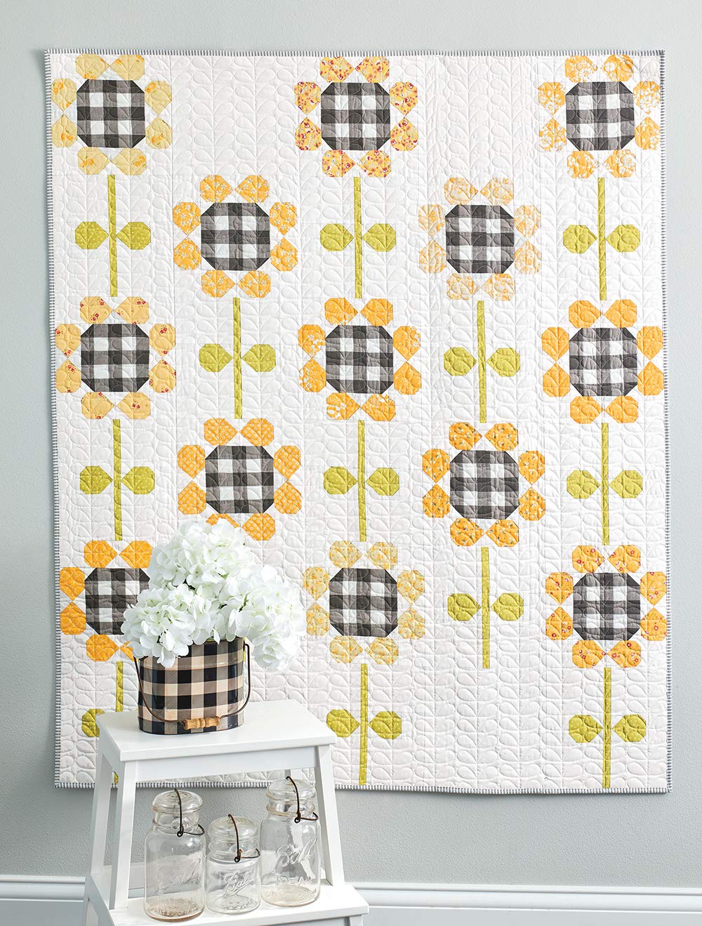 Quilt with black and white checkered flower pattern on a gray wall.
[additional_image_link]