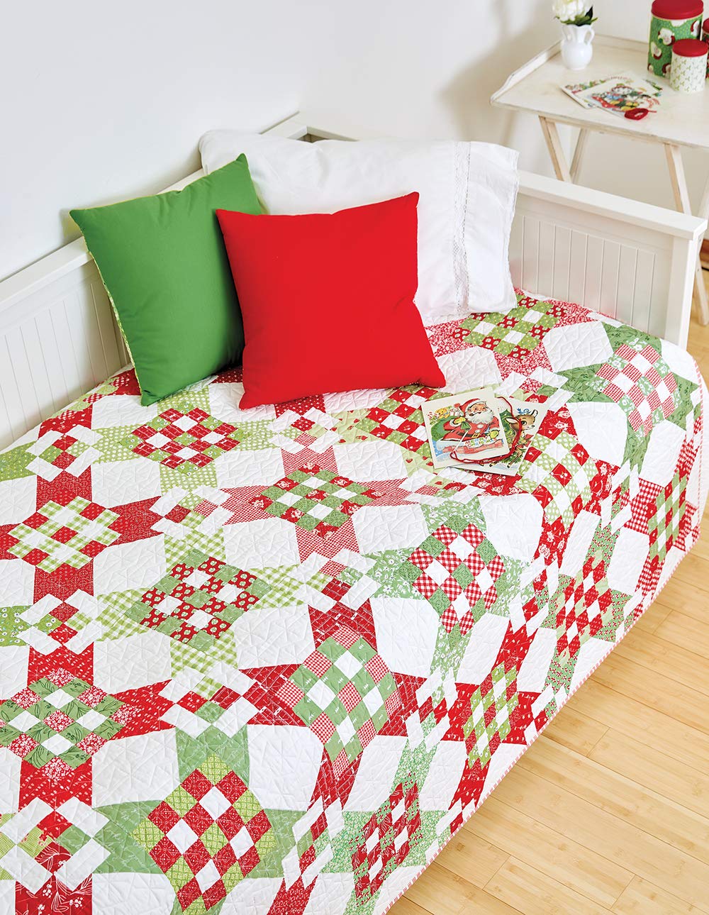 Bed with a red, green, and white patchwork quilt and pillows.
[additional_image_link]
