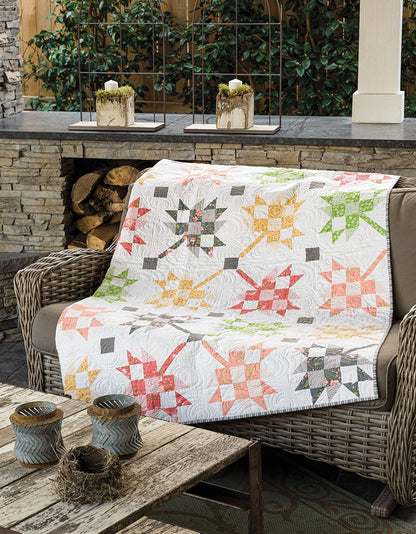 Quilt with star patterns draped over a wicker chair outdoors.
[additional_image_link]