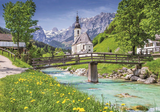 A wooden jigsaw puzzle depicting the Church of Ramsau in Springtime, with a bridge over a stream, surrounded by greenery and mountains in the background.
Photo by Wentworth Puzzles [image_link]