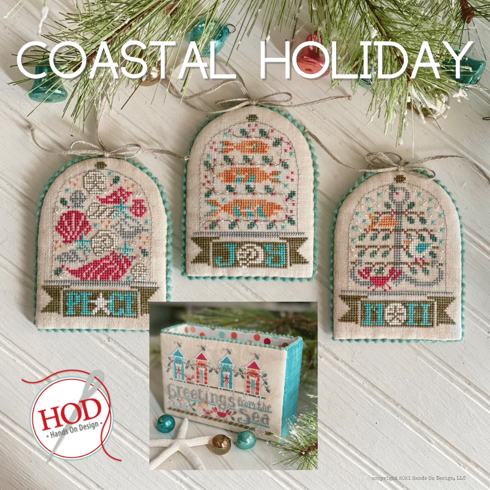 Three cross stitch embroidery ornaments with coastal and beach themes, and a storage box with the text 'Coastal Holiday' on a white background. The ornaments are hung by small green pine branches.
Photo by Handsondesign.com [image_link]