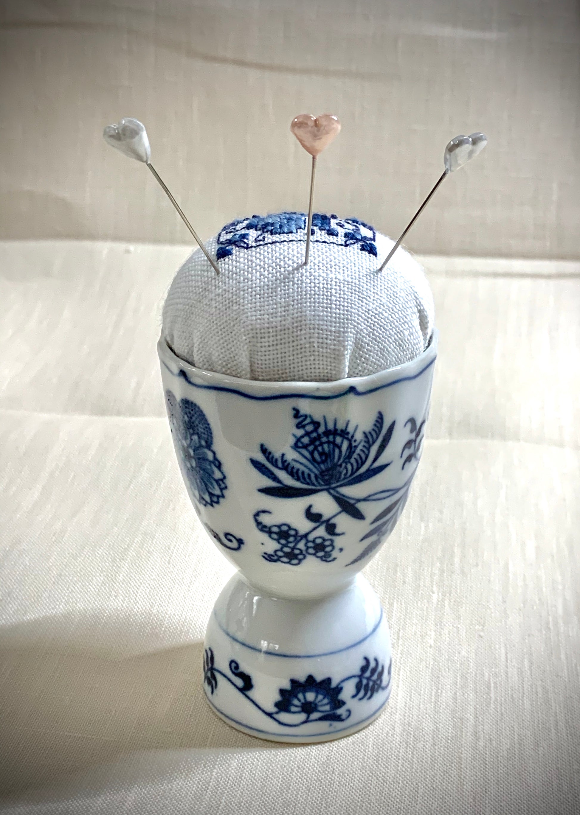 Hand stitched Delft pincushion on white linen with a Vintage Blue Danube Double Egg Cup from Japan, embroidered in blue and white colors.
Photos by The Surgeon's Knots [additional_image_link]