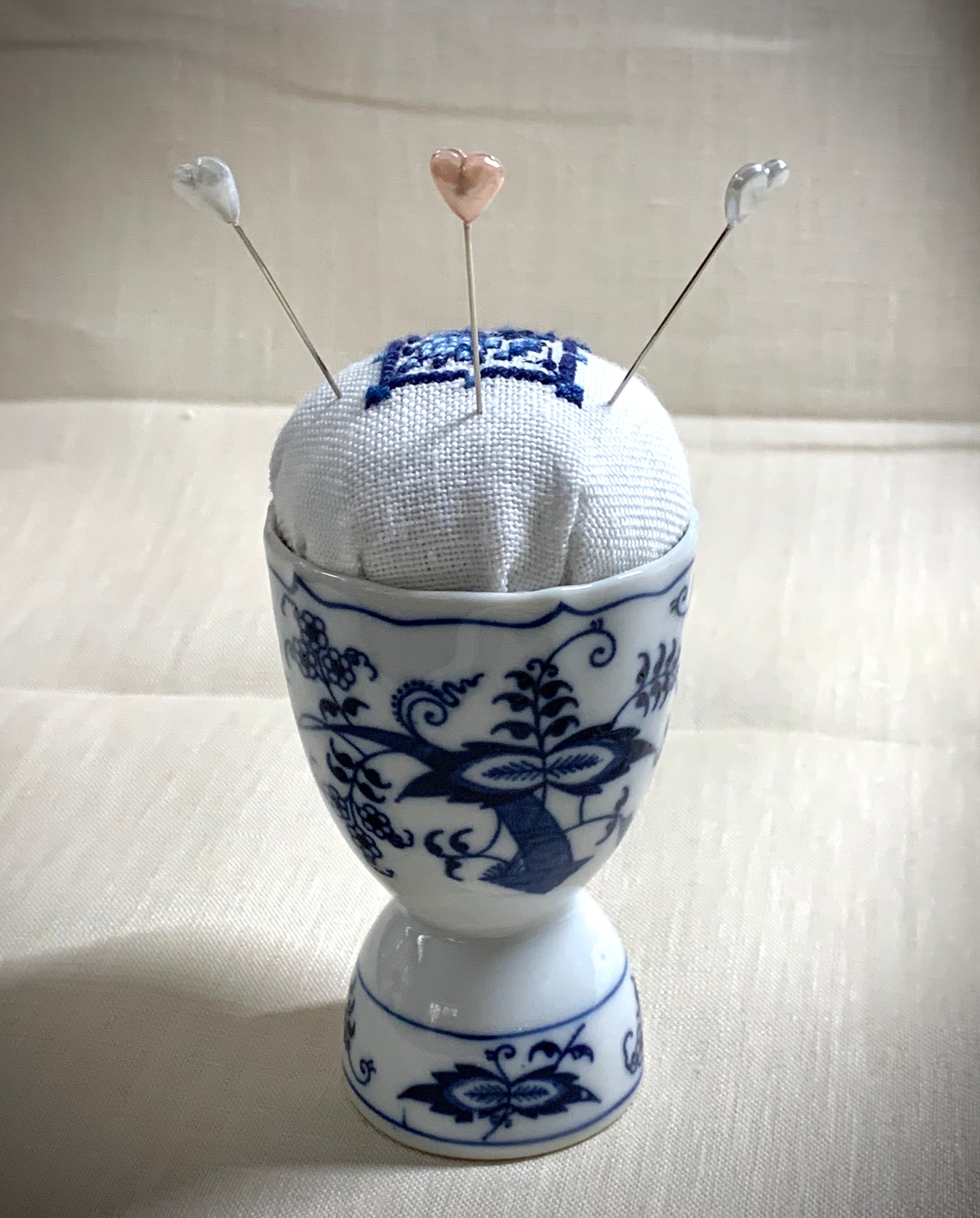 Hand stitched Delft pincushion in a vintage blue Danube double egg cup on white linen, with a signature pattern by Blue Danube in Japan.
Photos by The Surgeon's Knots [additional_image_link]