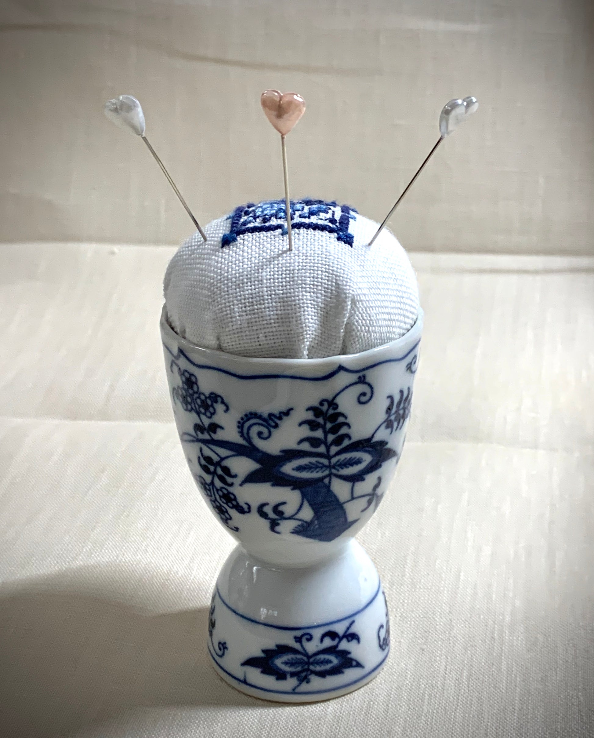 Hand stitched Delft pincushion in a vintage blue Danube double egg cup on white linen, with a signature pattern by Blue Danube in Japan.
Photos by The Surgeon's Knots [additional_image_link]