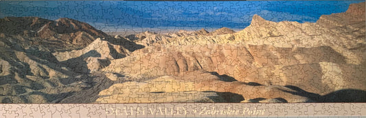 A jigsaw puzzle depicting a panoramic view of the Death Valley landscape, including the Zabriskie Point area, with a blue sky and distant mountains.
Photo by Karen King [image_link]