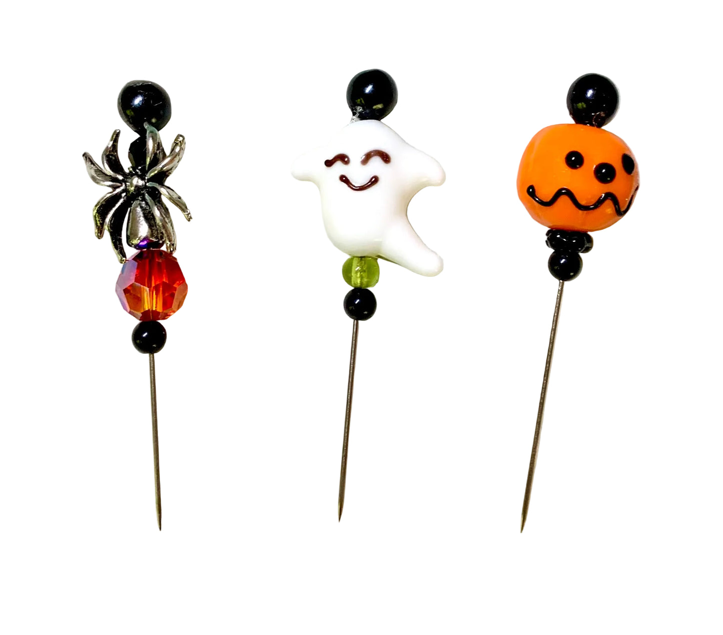 Three Halloween-themed beads on metal pins, featuring a silver spider, a white smiling ghost, and an orange jack-o'-lantern bead, displayed on a white background.
[image_link]