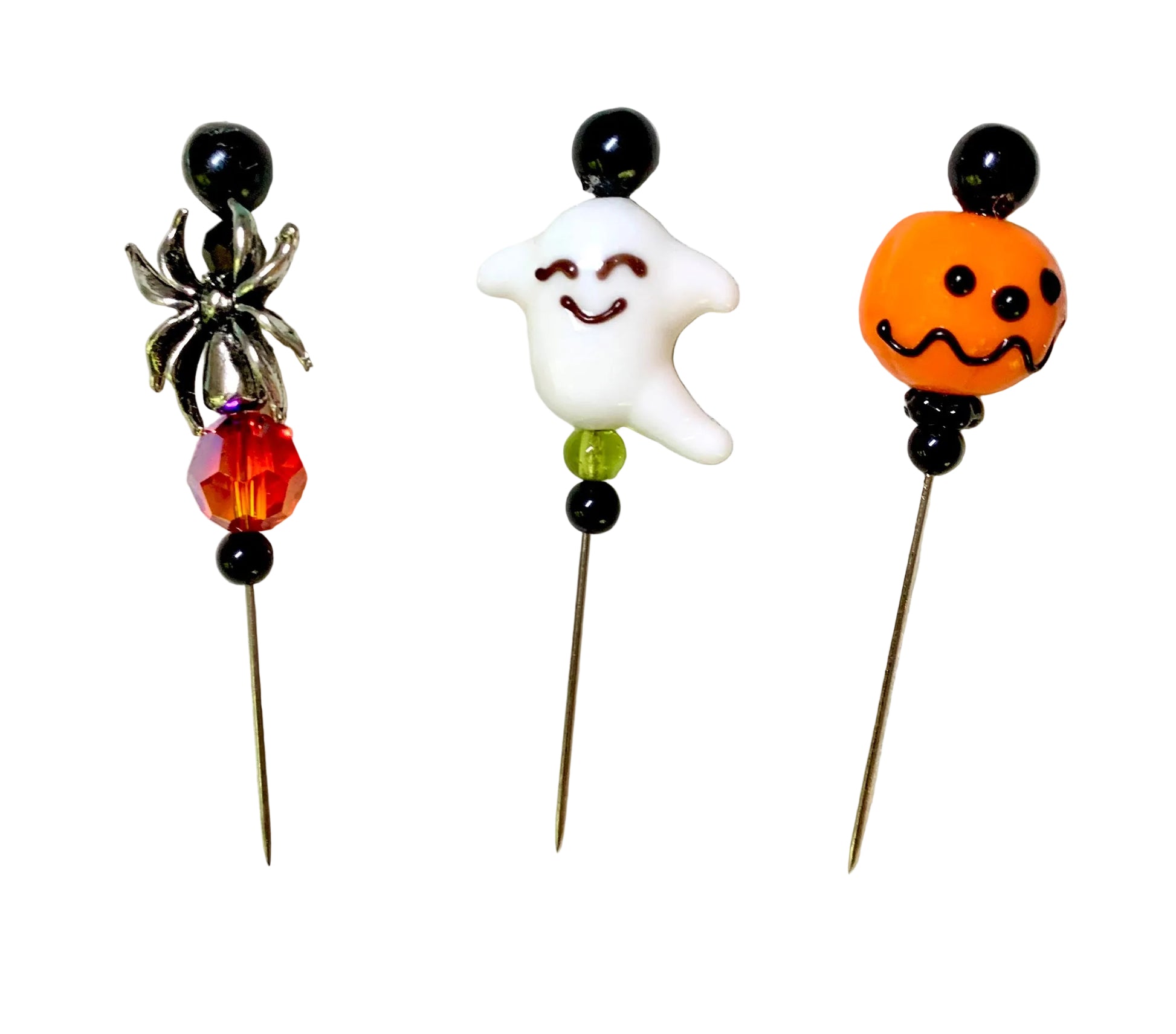 Three Halloween-themed bead pins on a white background. The left pin features a black bead top, a silver spider charm, and an orange faceted crystal bead. The right pin has a jack-o'-lantern lampwork bead. The middle has a smiling ghost bead.
[additional_image_link]