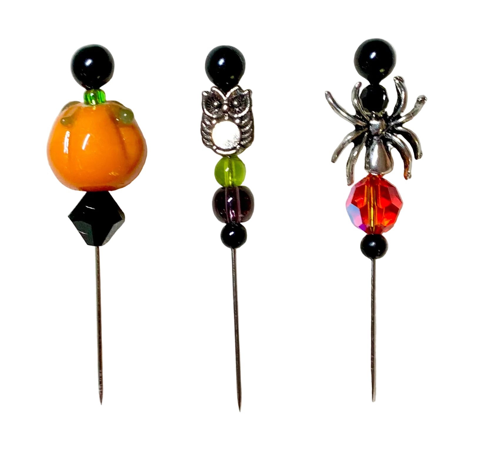 Three Halloween-themed beaded pins on a textured white background. The left pin features an orange pumpkin bead and a black faceted gem.
[additional_image_link]