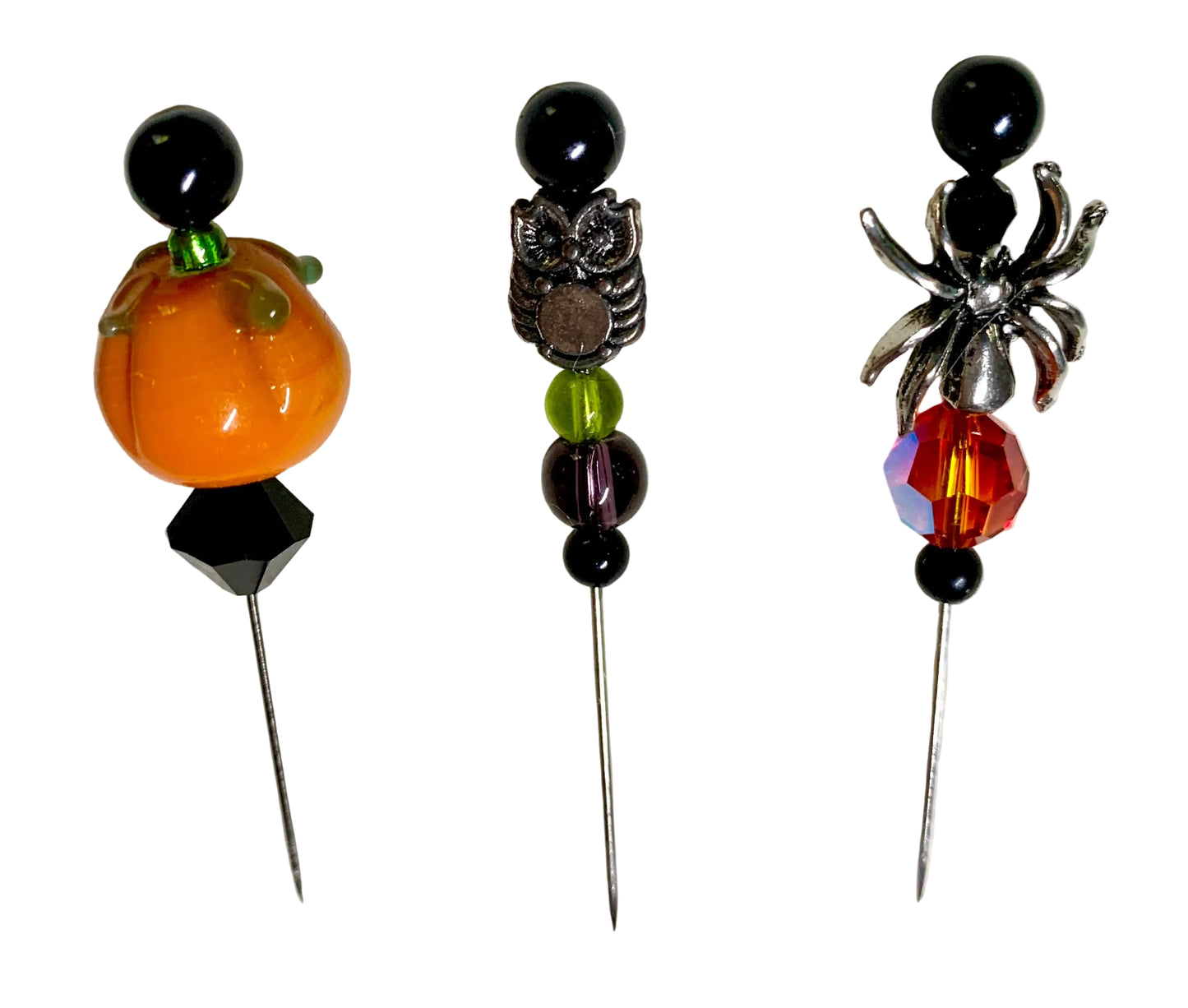 Three Halloween-themed beaded pins on a white background: an orange pumpkin with green stem, a silver owl, and a silver spider with a faceted orange crystal.
[additional_image_link]