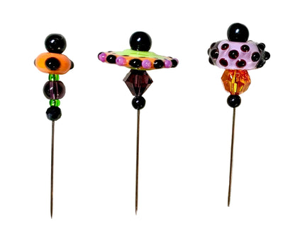 Three colorful beaded pins with long metal needles, displayed on a white surface. The pins feature unique bead designs in orange, lime green, purple, pink, and amber.
[additional_image_link]