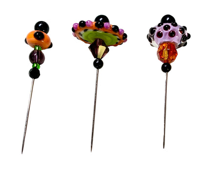 Three decorative beaded pins with long metal needles, displayed on a white background. The pins feature colorful glass beads in orange, purple, green, black, and white.
[additional_image_link]