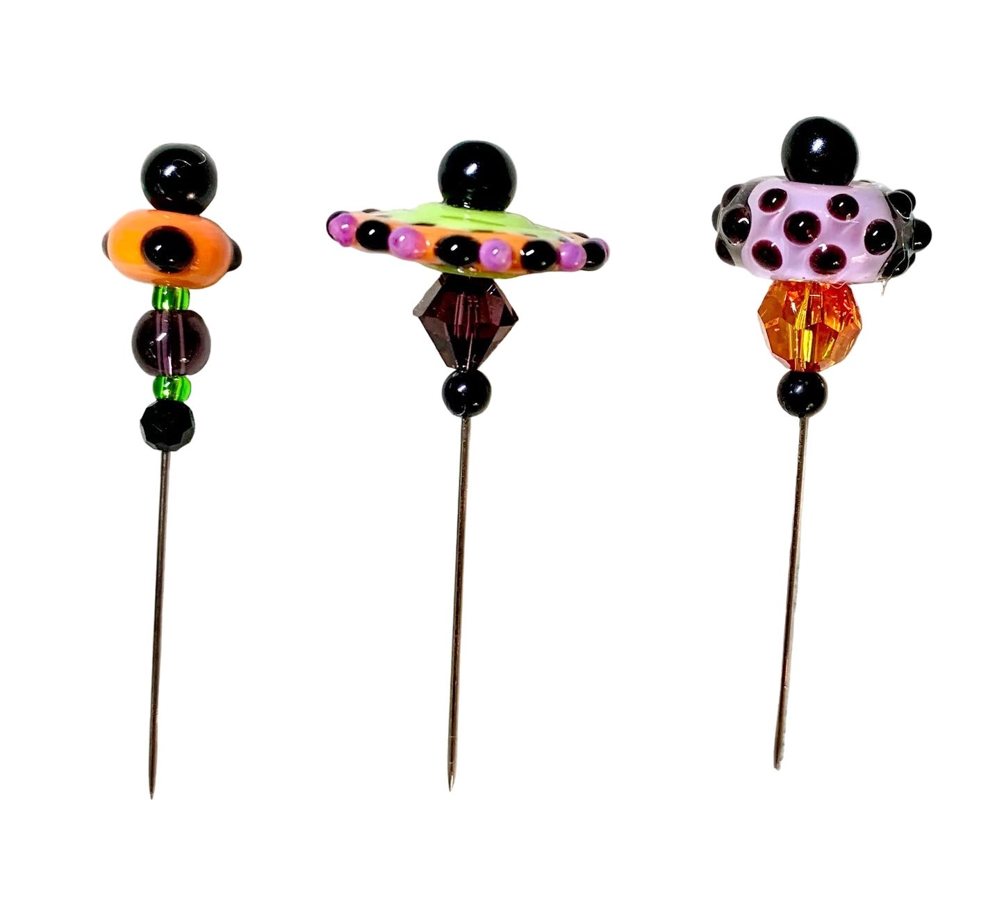 Three decorative beaded pins with long metal needles, displayed on a white background. Each pin features a unique colorful bead design topped with a black sphere.
[additional_image_link]