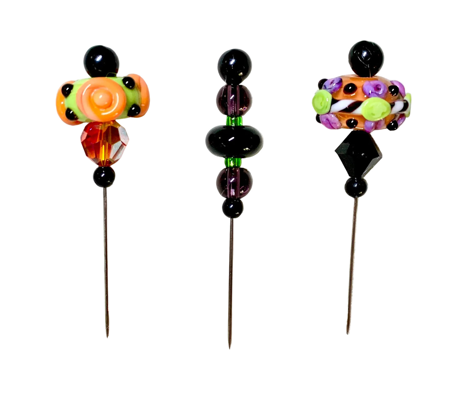 Three handmade glass bead pins, displayed on a white background. The pins feature colorful glass beads in orange, green, purple, black, and clear glass.
[additional_image_link]