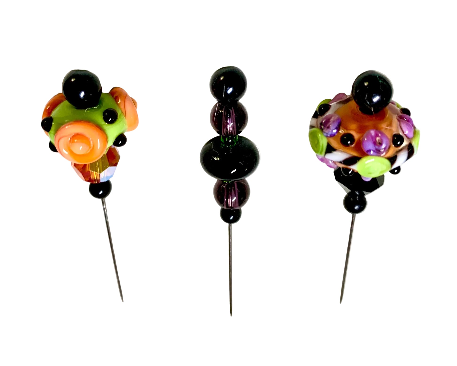 Three handmade glass bead pins with black beads and colorful glass tops, displayed on a white background.
[additional_image_link]