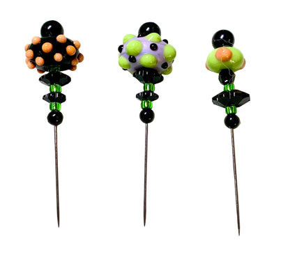 Three handmade glass bead pins with long metal needles, decorated with colorful glass beads and black faceted beads, displayed on a white background.
[additional_image_link]