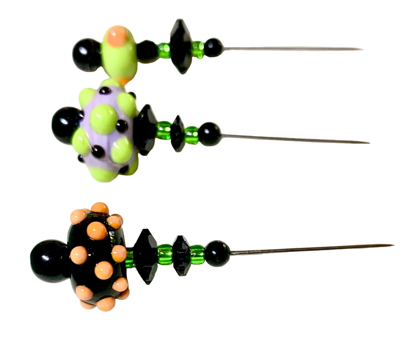 Three handmade beaded pins with long metal needles, featuring black beads, green faceted beads, and colorful glass lampwork beads in lime green, lavender, and peach, displayed on a white surface.
[additional_image_link]