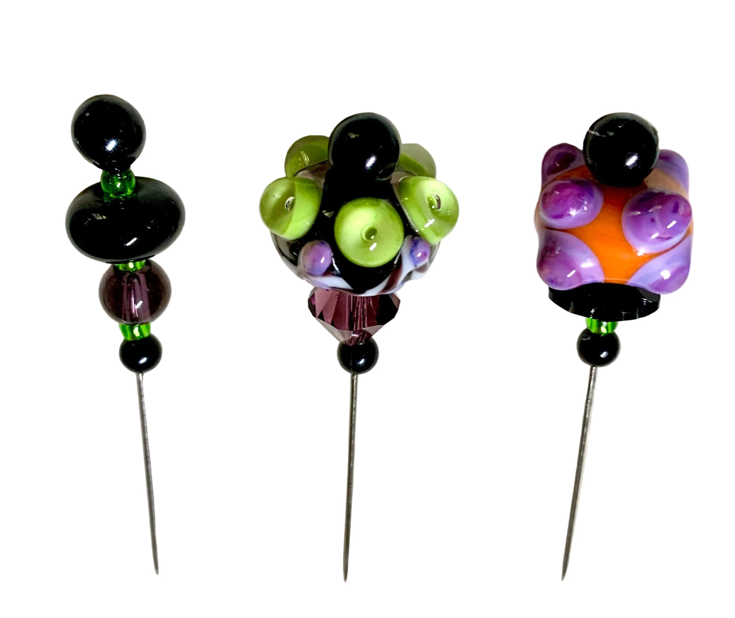 Three handmade beaded pins with long metal needles, displayed on a white background. The left pin features black beads and a small green accent.
[additional_image_link]