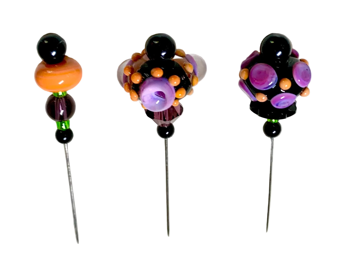 Three decorative beaded pins with long metal needles, featuring black beads, orange and purple glass beads, and small green accents on a white background.
[additional_image_link]
