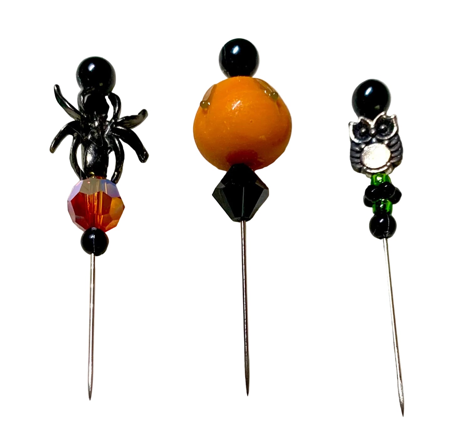 Three Halloween-themed beaded pins displayed on a white background. The left pin features a black spider with a faceted fire bead, a orange lampwork pumpkin with a black bicone bead.
[additional_image_link]