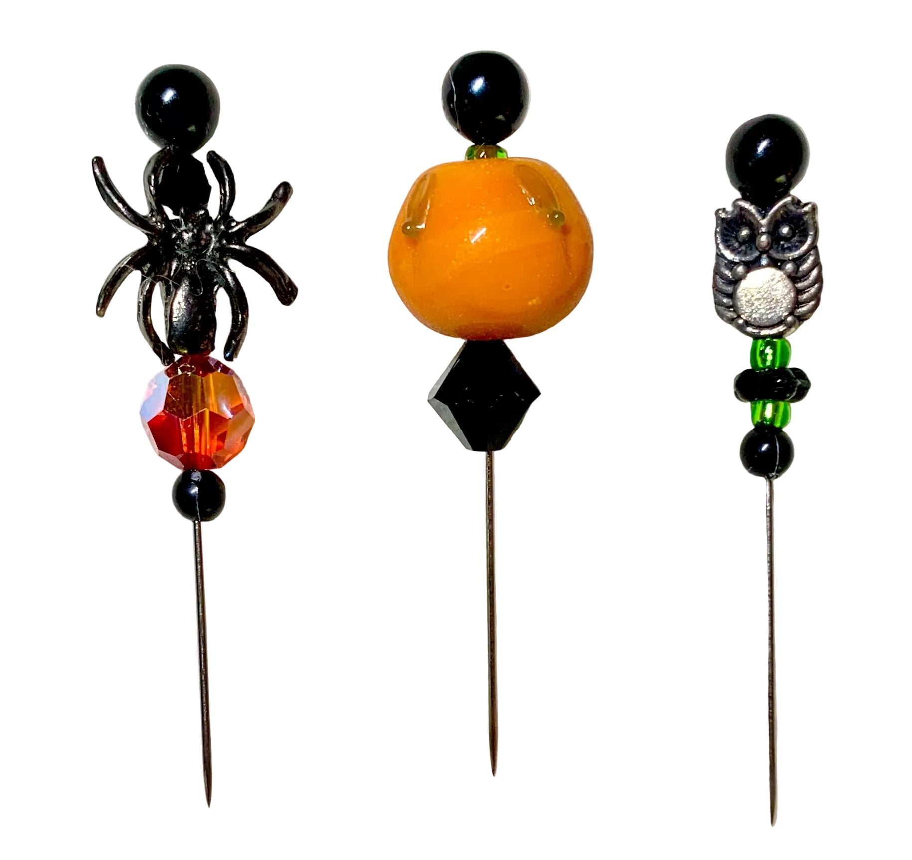 Three Halloween-themed beaded pins on metal needles, featuring a silver spider, a glossy orange pumpkin, and a silver owl with green beads, displayed on a white background.
[additional_image_link]