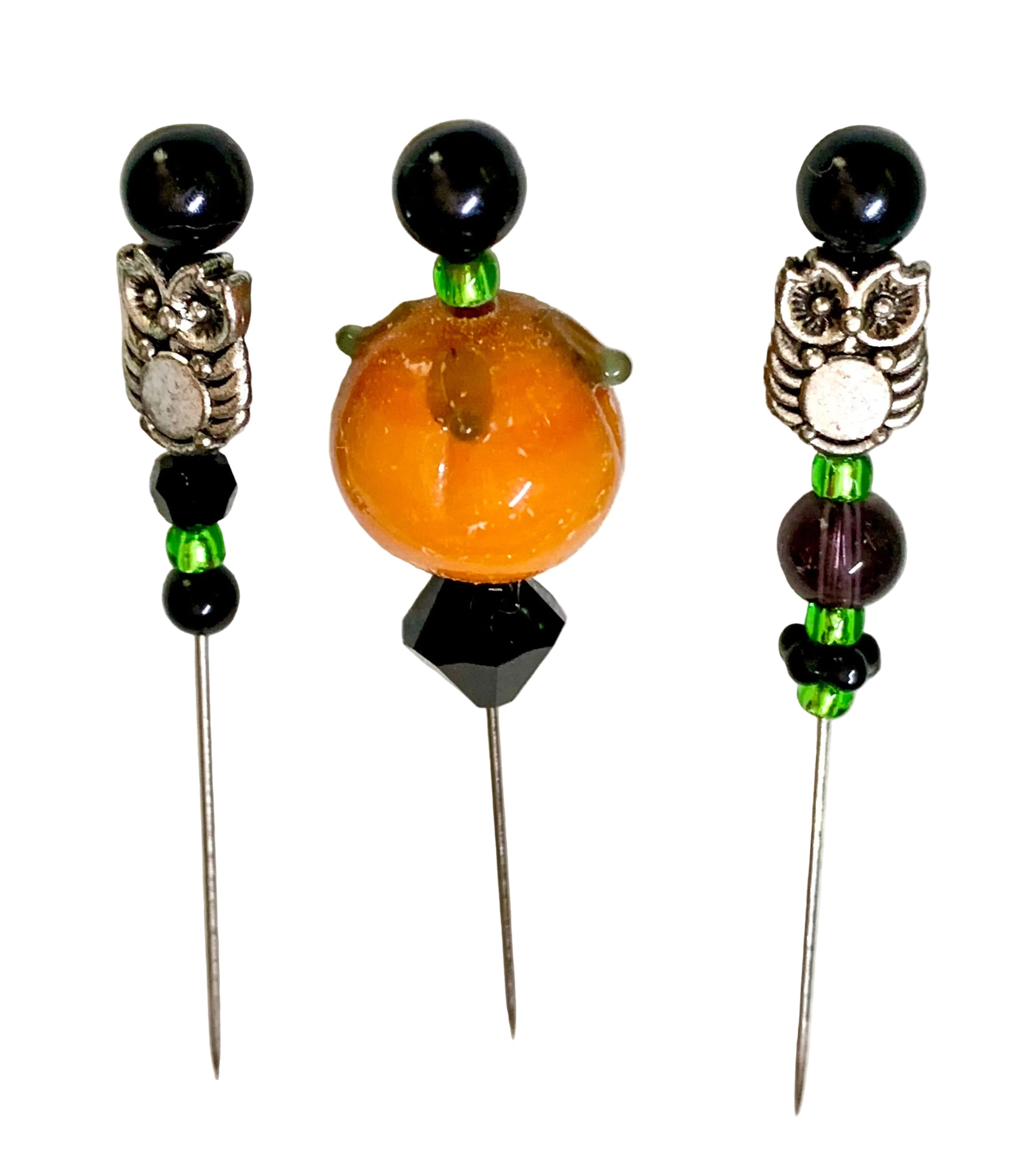 Three beaded sewing pins displayed on a white surface. Two pins feature black beads, silver-toned owl charms, and green spacer beads, while the center pin features a large orange pumpkin bead with a black faceted bead below it.
[additional_image_link]