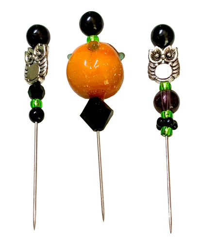 Three decorative sewing pins with long metal needles, featuring black beads, green spacer beads, silver owl charms, and a central orange pumpkin bead, displayed on a white background.
[additional_image_link]