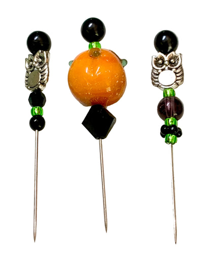Three beaded pins laid flat on a white surface. Each pin has a black beads, a decorative silver owl and ornamental bead, small green spacer beads, and colored accent beads.
[additional_image_link]
