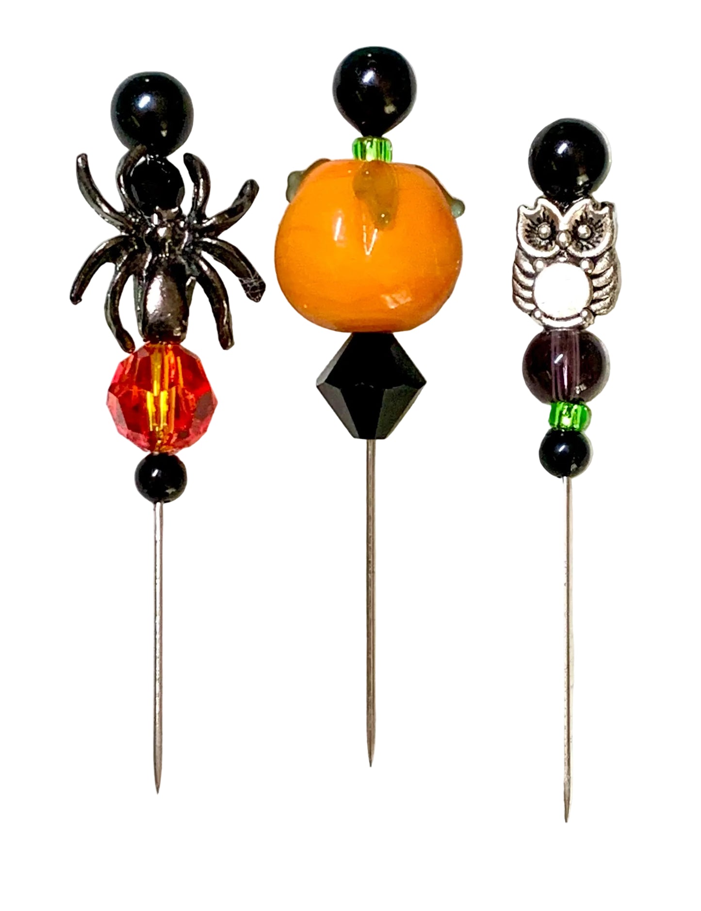 Three Halloween-themed beaded pins on silver metal sticks, featuring a black spider, an orange pumpkin, and a silver owl design, set against a white background.
[image_link]