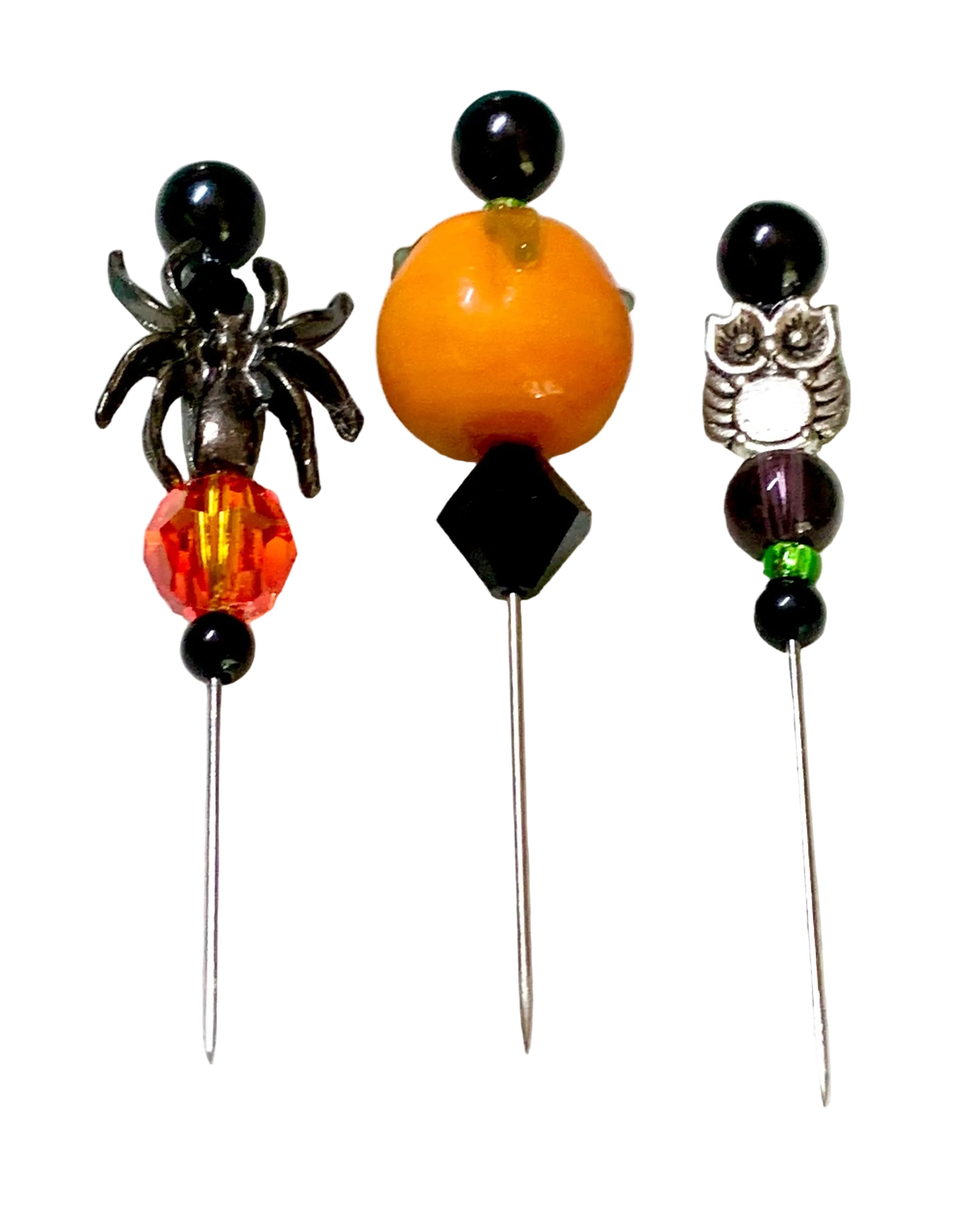 Three decorative sewing pins with Halloween-themed designs, including a black spider, an orange bead, and a silver owl, displayed on a white surface. The middle bead is a pumpkin. The right pin has a silver owl.
[additional_image_link]