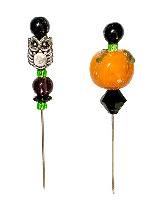 Two decorative metal pins with beaded tops on a white background. One pin features a silver owl charm, a dark purple bead, and green beads at the top. The other is a pumpkin.
[image_link]