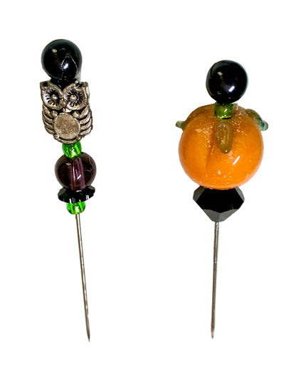 Two Halloween-themed beaded pins on a white background. One pin features a silver owl charm, a dark purple bead, and a black top bead. The other is a pumpkin.
[additional_image_link]