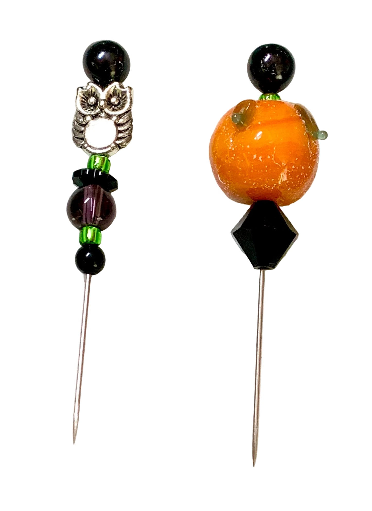 Two beaded sewing pins on a white background. One pin features a silver owl charm with a white eye and black beads. The other is a pumpkin.
[additional_image_link]