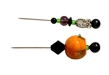 Two beaded sewing pins displayed on a white background. One pin features a large orange pumpkin bead, a black faceted bead, and a black round bead. The other is an owl.
[additional_image_link]