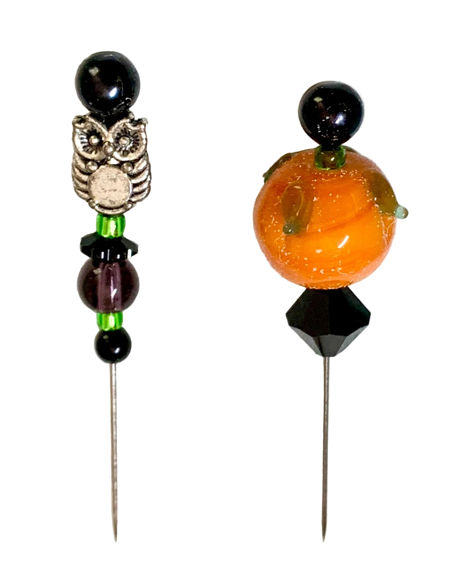 Two decorative beaded pins on a white background. The left pin features a silver owl charm, black beads, and a purple faceted bead. The other is a pumpkin.
[additional_image_link]