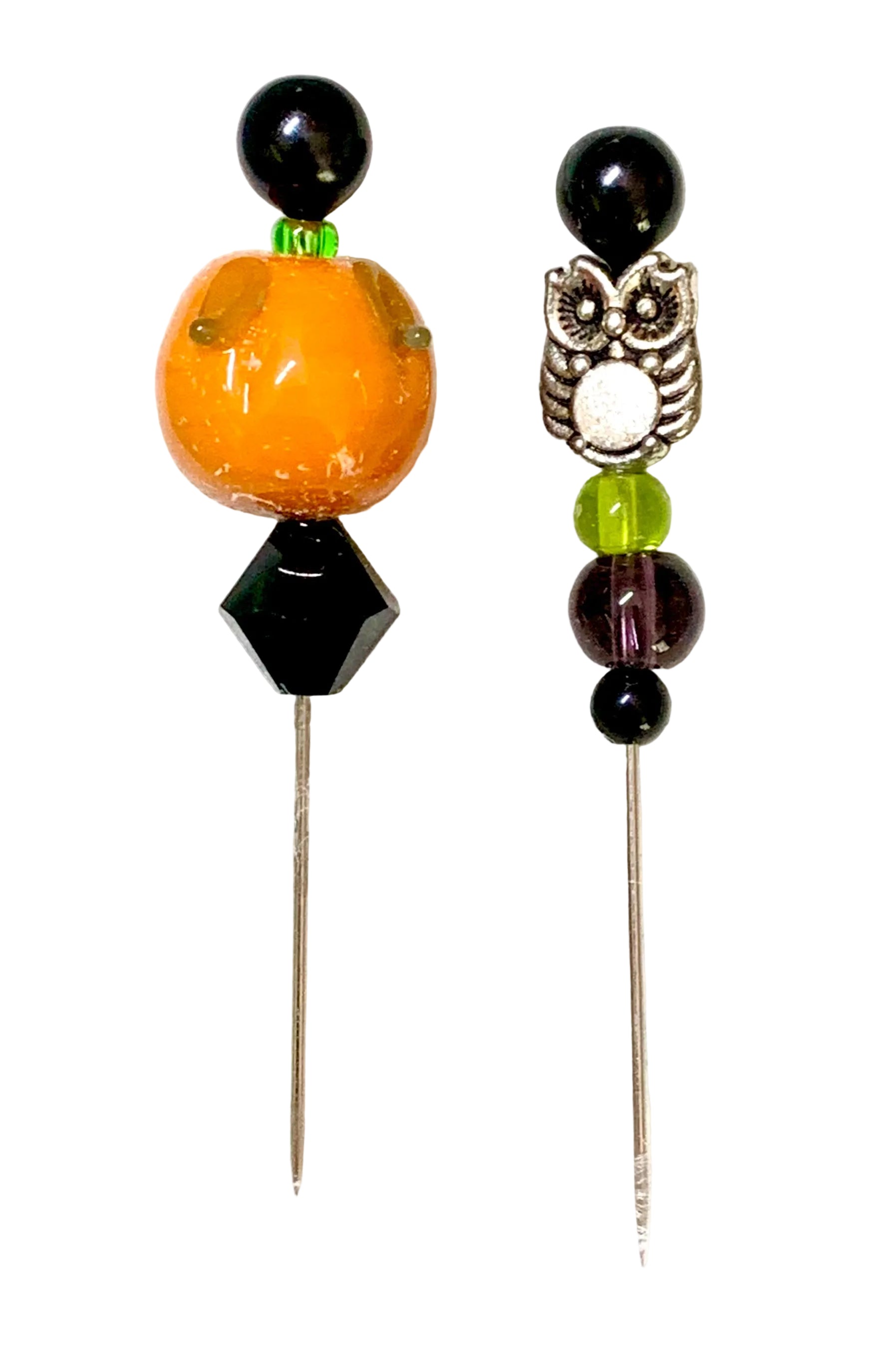 Two beaded pins on a white background. One pin features a large orange pumpkin bead, a black faceted bead, and a small green accent. The other is an owl.
[additional_image_link]