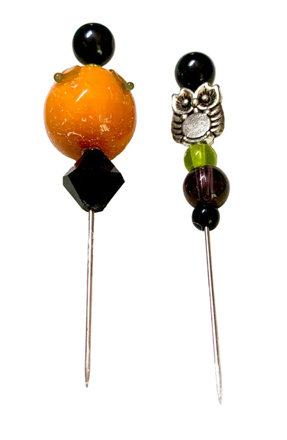 Two beaded pins on a white background. One pin features a large orange bead, a black faceted bead, and a black sphere. The other is an owl.
[additional_image_link]