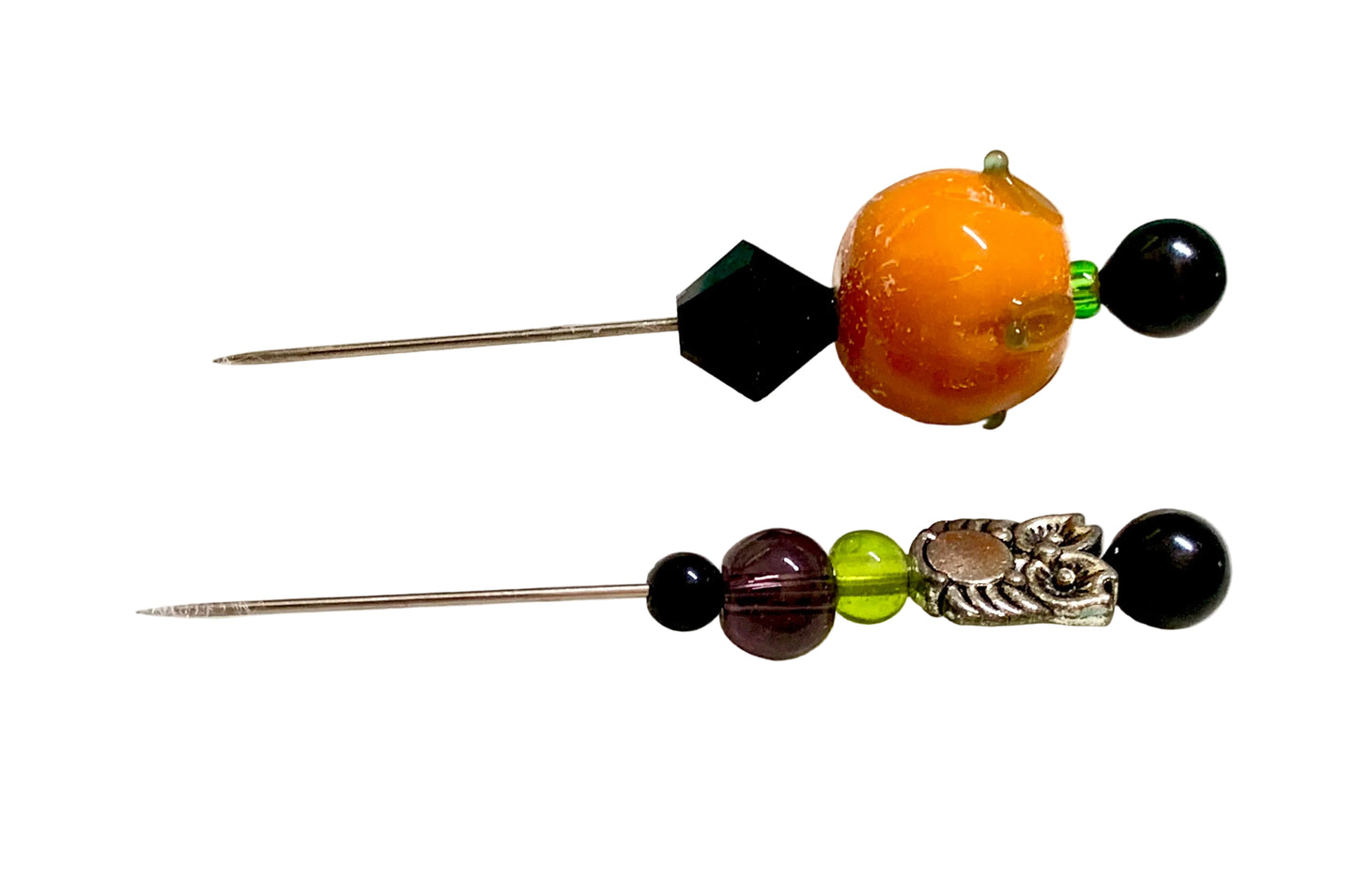 Two decorative sewing pins with beaded accents, one featuring a large orange pumpkin bead and a black faceted bead, and the other featuring a purple bead, a green bead, and a silver owl accent, displayed on a white surface.
[additional_image_link]