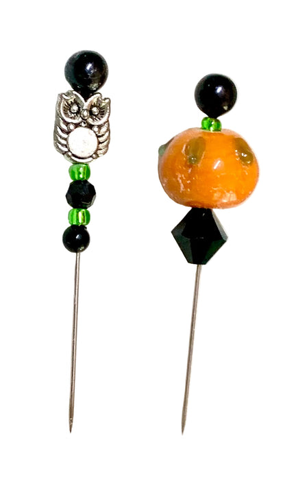 Two beaded pins, featuring black beads, green spacer beads, a silver owl charm on the left, and an orange pumpkin bead with a black faceted accent on the right, set against a white background.
[additional_image_link]