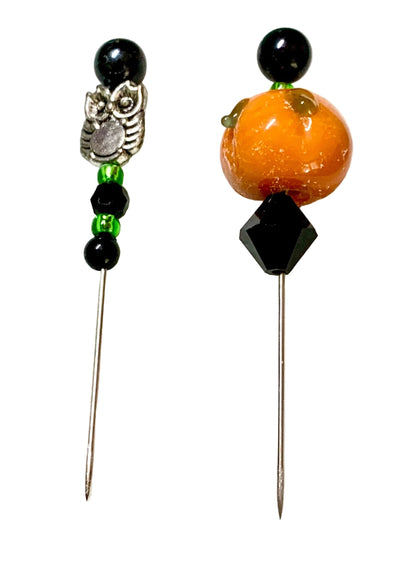 Two Halloween-themed sewing pins on a white background. One pin features a silver-toned owl charm, black beads, and green beads. The other is a pumpkin.
[additional_image_link]