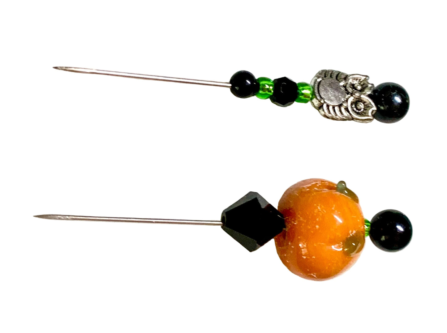 Two beaded pins, featuring black beads, green accent beads, a silver owl charm on the left, and an orange pumpkin bead with a black faceted diamond accent on the right, displayed on a white background.
[additional_image_link]