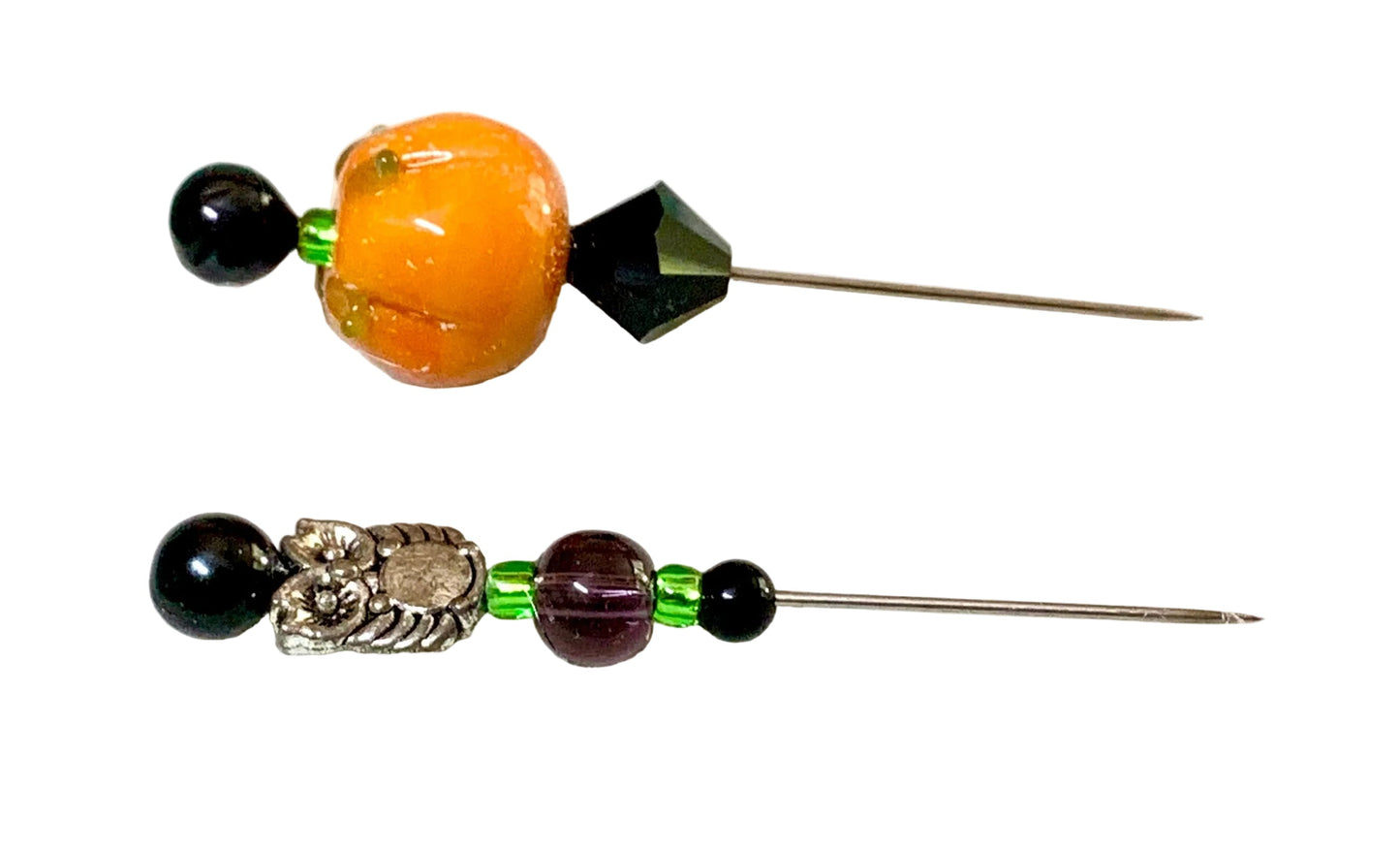Two handmade beaded pins displayed on a white background. One pin features a silver owl charm, a dark purple bead, and a black bead at the top. The other is a pumpkin.
[additional_image_link]