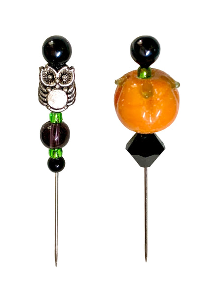 Two Halloween-themed beaded pins on a white background. One pin features a silver owl charm with a white center, black beads, and green accents. The other pin is a pumpkin.
[additional_image_link]