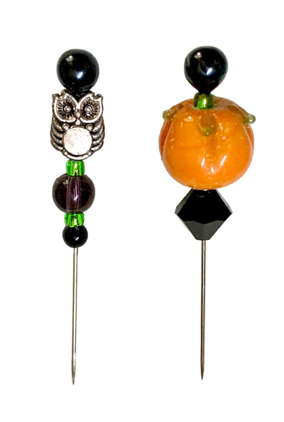 Two Halloween-themed beaded pins on a white background. One pin features a silver owl with black and white details, green beads, and black beads. The other is a pumpkin.
[additional_image_link]