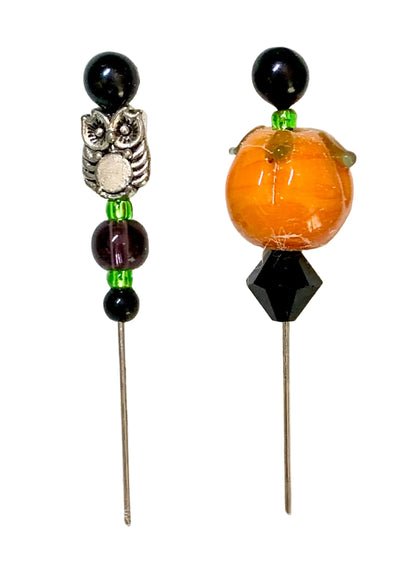 Two Halloween-themed beaded pins on a textured white background. One pin features a silver owl charm with black beads and green accents. The other pin is a pumpkin.
[image_link]